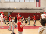 Youth baseball players warming up in a high school gym